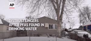Photo of a house with snow on the ground and a chain link fence that has the text, "Distrust lingers as PFAS found in drinking water."