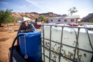Kayto Sullivan Sr. sits on the tailgate of his truck while filling hundreds of gallons’ worth of containers with water from a spigot this month in Goulding, Utah.