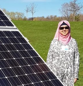 A photo of Huda Alkaff next to a solar panel outside
